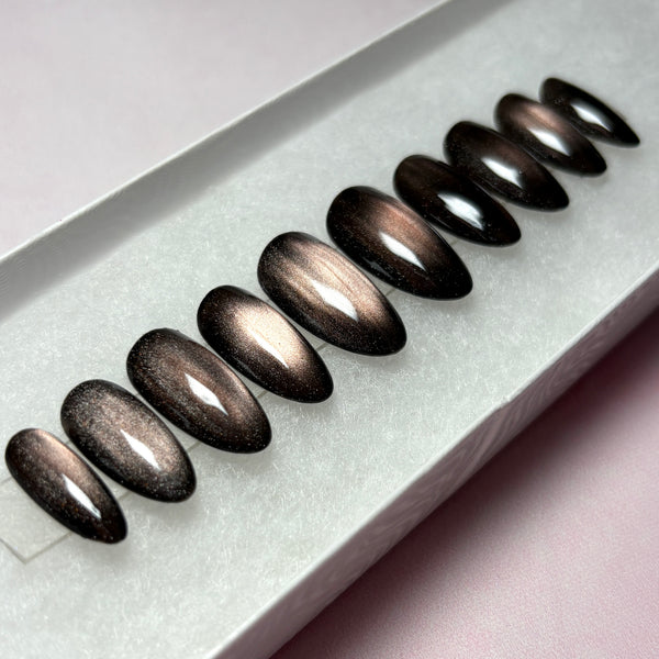Load image into Gallery viewer, Press-on nails featuring a dark metallic cat-eye finish that shifts from burnished bronze to deep brown-black, in a short almond shape, handmade by Illuminate by Liana Press-On Nails UK.