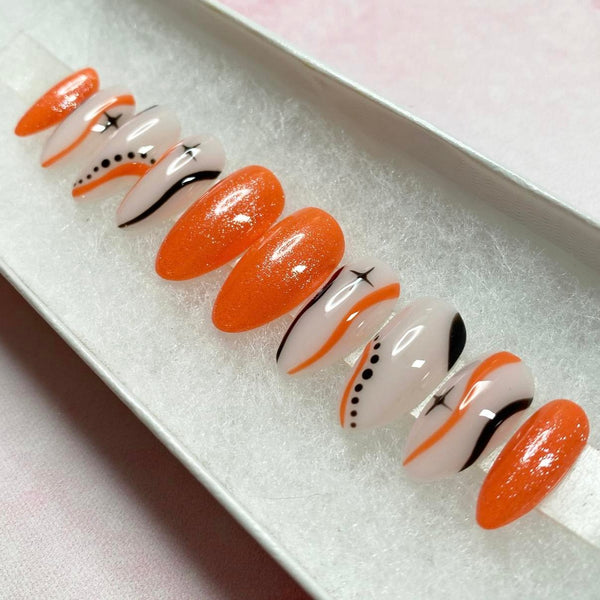 Load image into Gallery viewer, Handmade false nails in orange and black, featuring stars, wavy lines and dots, on a natural colour base, and subtle glitter.