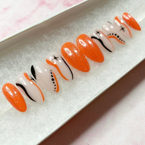 Load image into Gallery viewer, Press-on nails with an orange and black design, featuring stars and wavy lines on a natural colour base, and subtle glitter, in a short almond shape.