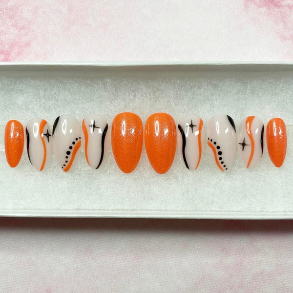 Load image into Gallery viewer, Short almond press-on nails with an orange and black design, featuring stars, wavy lines and dots, on a natural colour base, and subtle glitter.