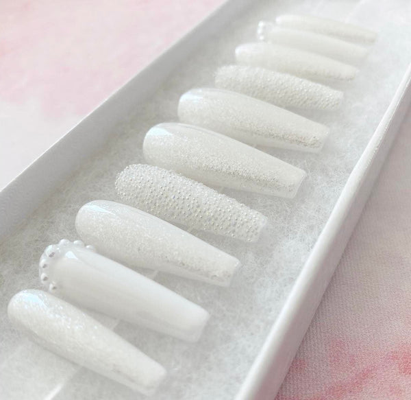 Load image into Gallery viewer, Handmade white false nails with pearl embellishments and tiny white caviar beads, on a shimmering glazed white base, in a long coffin shape.