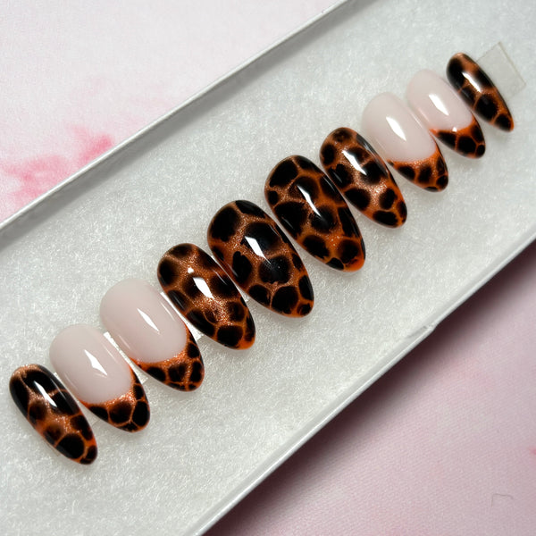 Load image into Gallery viewer, Press-on nails featuring an animal print design that resembles leopard print or tortoiseshell in copper and deep brown-black, as well as four French tip nails tipped with the same animal print pattern, handmade by Illuminate by Liana Press-On Nails UK.