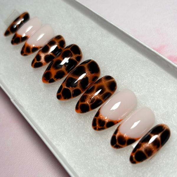 Load image into Gallery viewer, False nails featuring an animal print design that resembles leopard print or tortoiseshell in copper and deep brown-black, as well as four French tip nails tipped with the same animal print pattern, displayed in a white presentation box.
