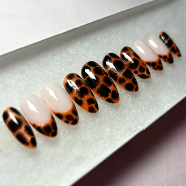 Load image into Gallery viewer, Animal print glue-on nails with a design that resembles leopard print or tortoiseshell in copper and deep brown-black, as well as four French tip nails tipped with the same animal print pattern, displayed in a white presentation box.