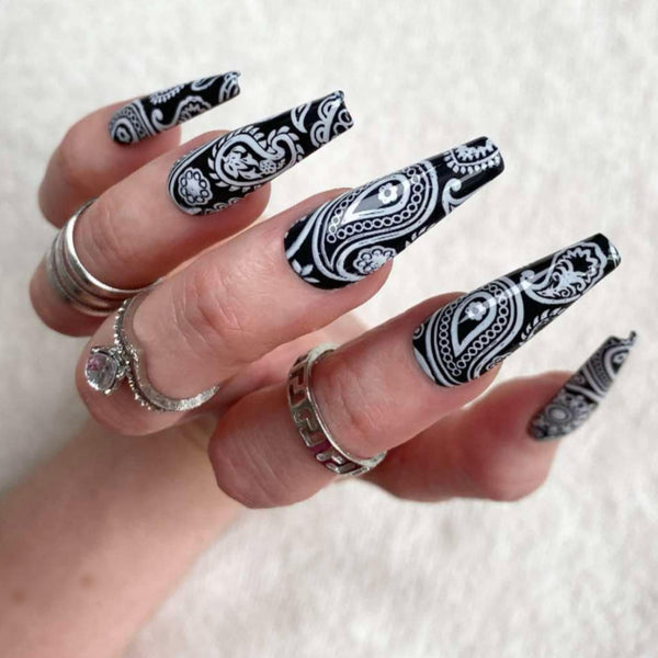 Load image into Gallery viewer, Hand wearing long press-on nails with a black and white paisley bandana design, and three silver rings, against a white background.