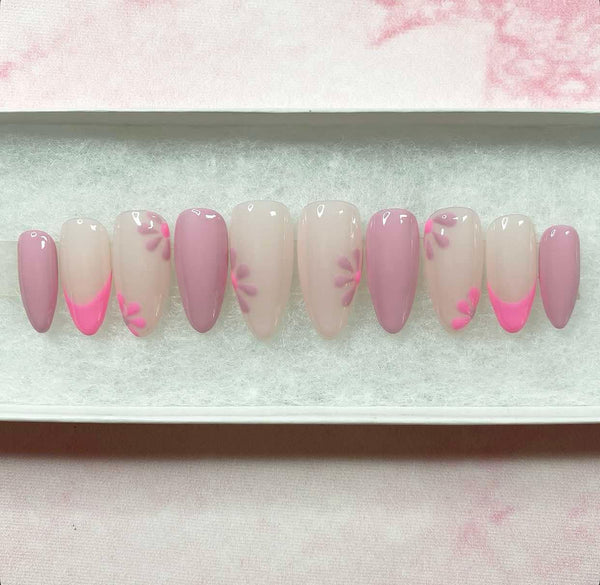 Load image into Gallery viewer, Handmade false nails in varying shades of pink and lilac with floral accents and French tips, displayed in a white presentation box, created by Illuminate by Liana.