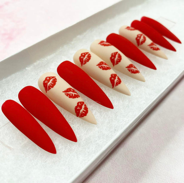 Load image into Gallery viewer, A set of press-on nails featuring a mix of matte red and nude nails with a pattern of red lips in a matte finish.