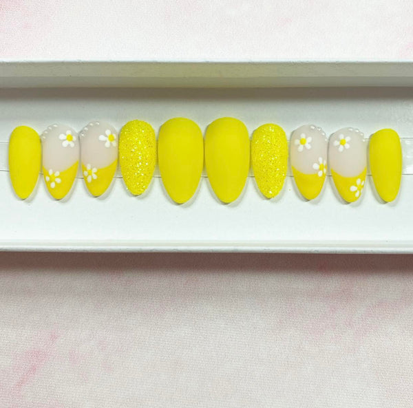 Load image into Gallery viewer, Short almond press-on nails featuring a yellow French tip design with a delicate daisy design and tiny white pearls, in a white presentation box.