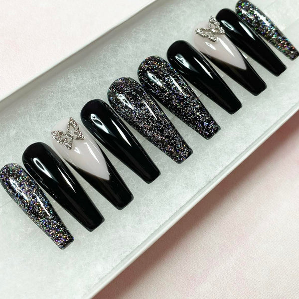 Load image into Gallery viewer, Set of long coffin black and glittery press-on nails with two silver butterfly gems and French tips.