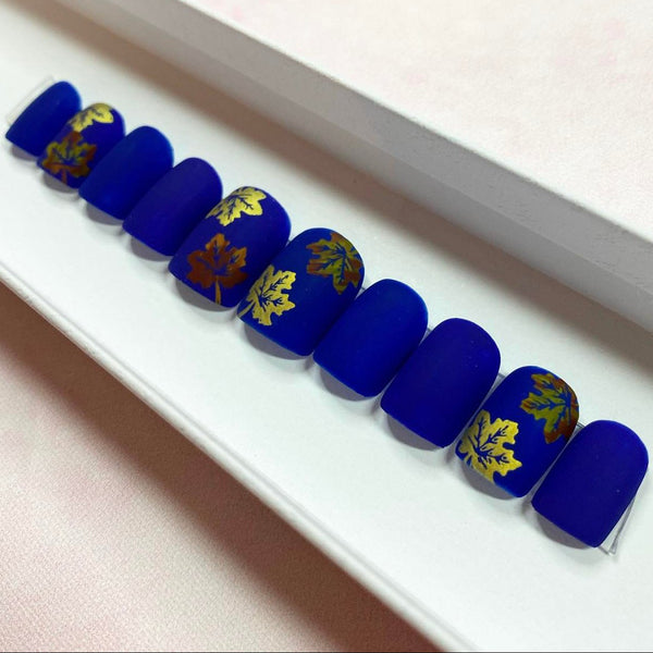 Load image into Gallery viewer, Short square Autumn fake nails in deep blue featuring an autumn leaves design in shimmering gold and copper tones, displayed in a white presentation box.