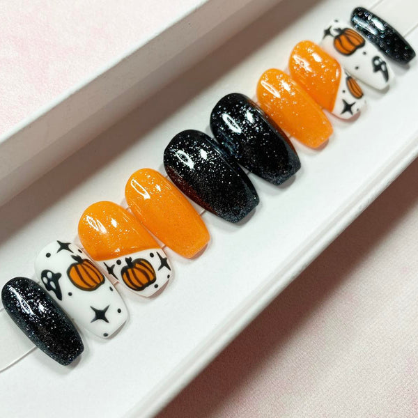Load image into Gallery viewer, Halloween false nails in a short coffin shape, in black, orange and white colours, with various designs such as pumpkins, ghosts, and stars, with matte and glossy finishes and subtle glitter, displayed in a white presentation box.