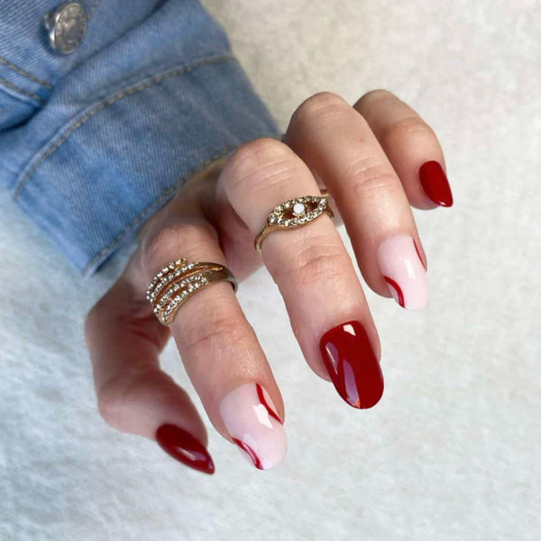 Load image into Gallery viewer, A hand wearing press-on nails painted in a deep burgundy red color with natural tips and burgundy lines, wearing gold rings.