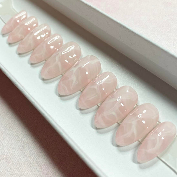 Load image into Gallery viewer, Handmade press-on nails that resemble rose-quartz gemstone crystals, in a soft pastel pink with a white marbling pattern throughout, displayed in a white presentation box.