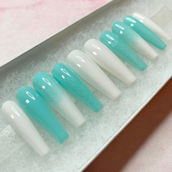 Load image into Gallery viewer, Teal blue and white press-on nails showcasing a white and blue ombre design with subtle glitter, in a long coffin shape, displayed in a white presentation box.
