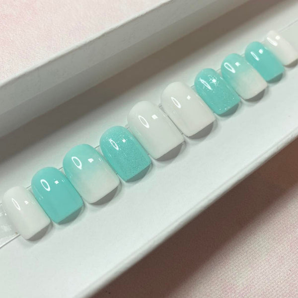 Load image into Gallery viewer, Short square pale blue and white press-on nails with a white and blue ombre design and subtle glitter, displayed in a white presentation box.