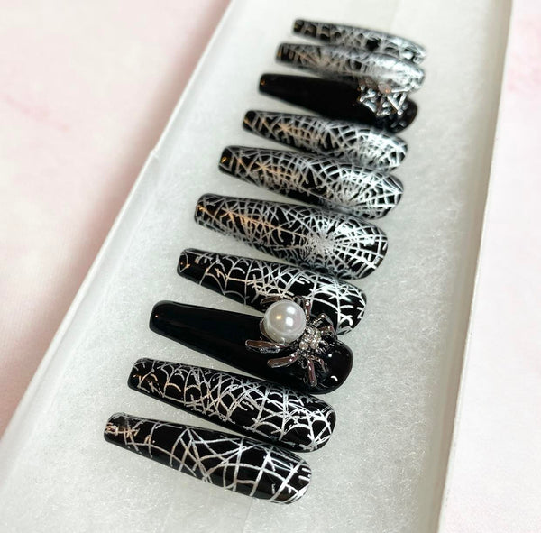 Load image into Gallery viewer, Long coffin Halloween press-on nails featuring a black and silver spider web design, with a 3D silver spider gem with a large white pearl on it, and a silver 3D spider web gem, displayed in a white presentation box.