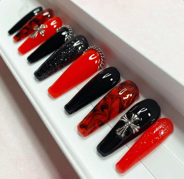 Load image into Gallery viewer, Gothic design press-on nails in red and black with silver chains and silver cross gems, a marble black-red pattern, and subtle glitter, in a long coffin shape.