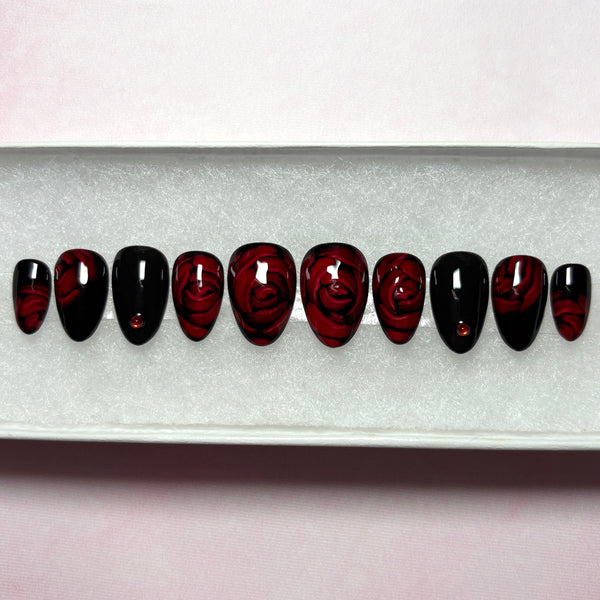 Load image into Gallery viewer, Short floral handmade press-on nails with 3D effect roses in dark red and black, adorned with delicate red rhinestones, in a short almond shape, from Illuminate by Liana UK.