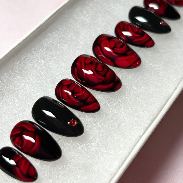 Load image into Gallery viewer, Red and black floral press-on nails with 3D effect roses in dark red and delicate red rhinestones, in a short almond shape, displayed in a white presentation box.