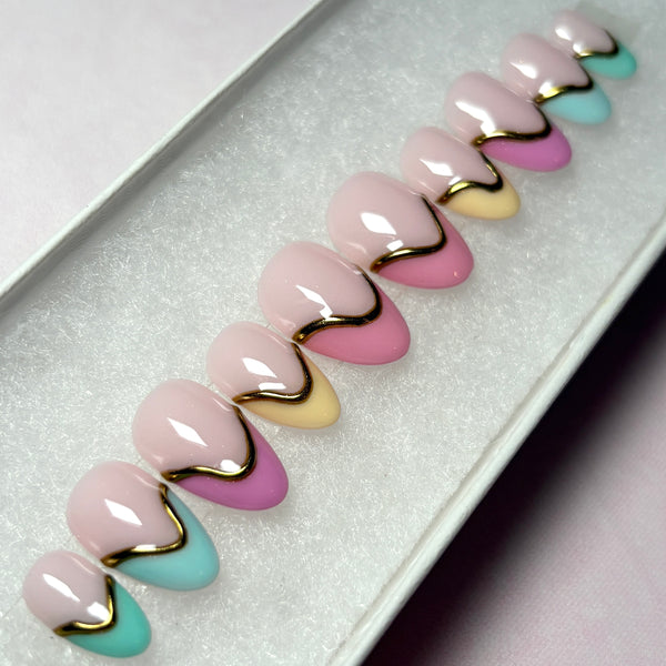 Load image into Gallery viewer, Short almond French tip press-on nails in soft pastel shades of teal, blue, raspberry and peachy pink, and yellow, featuring 3D gold chrome accents on each nail.