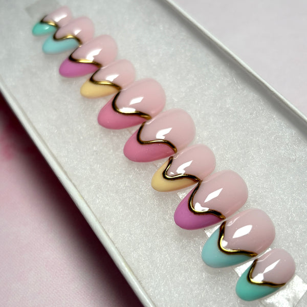 Load image into Gallery viewer, Spring Summer press-on nails in a French tip design, in soft pastel shades, featuring 3D gold chrome accents on each nail, in a short almond shape and displayed in a white presentation box.