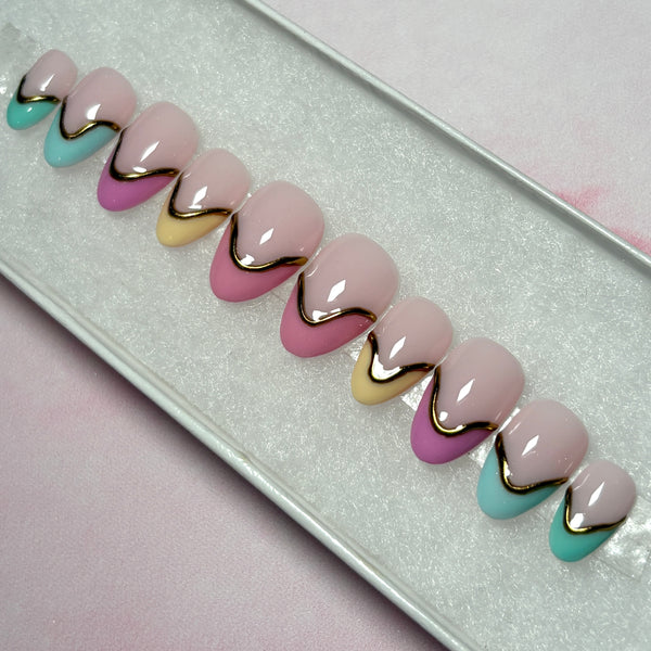 Load image into Gallery viewer, French tip handmade false nails in soft pastel shades of pinks, yellow and teal, featuring 3D gold chrome accents on each nail, in a short almond shape and displayed in a white presentation box.