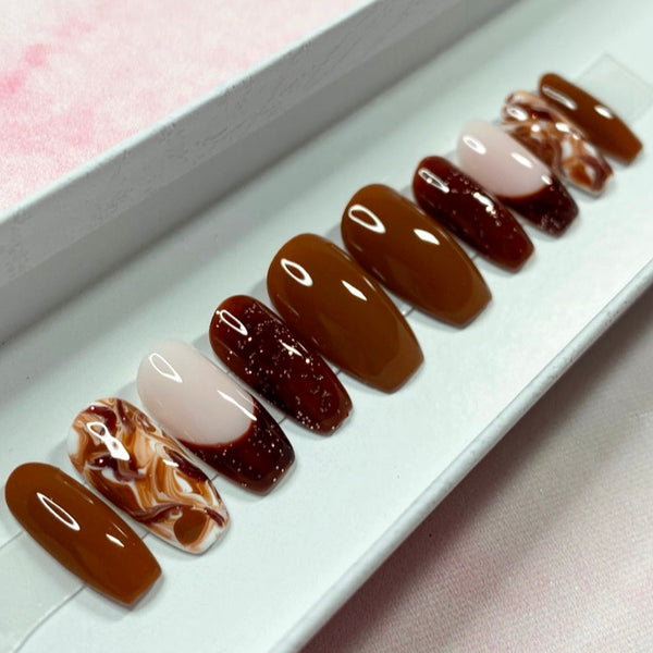 Load image into Gallery viewer, Short coffin handmade French tip press-on nails in various tones of brown with subtle glitter and a marble effect pattern on the ring fingers.