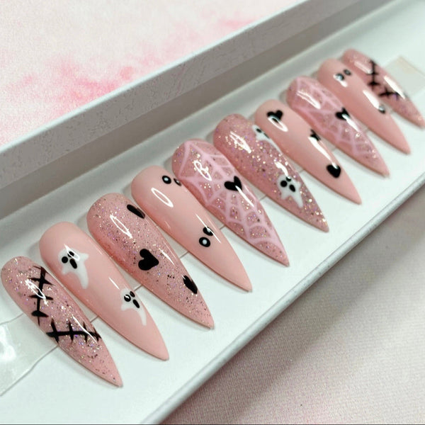 Load image into Gallery viewer, Halloween press-on nails in pink featuring Halloween designs including black scars and hearts, white ghosts, spooky eyes, and a pink spiderweb with a black heart at the centre, as well as pink glitter, displayed in a white presentation box.