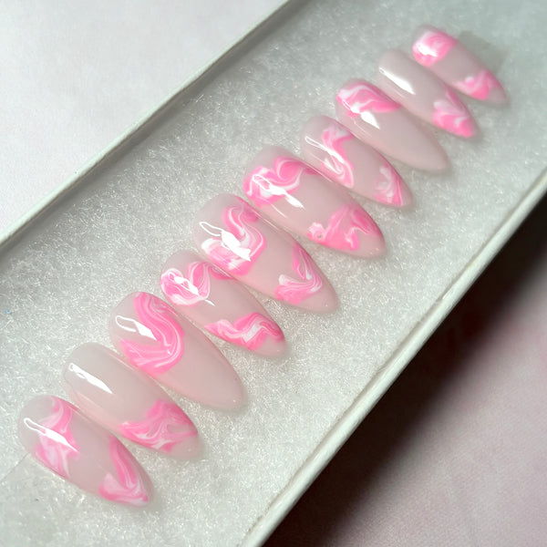 Load image into Gallery viewer, Soft pink press-on nails in a long almond shape with swirls of pink and white marble effect on each nail, displayed in a white presentation box