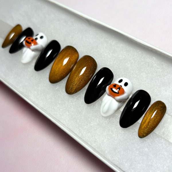 Load image into Gallery viewer, Handmade false nails for Halloween, featuring glossy black, metallic coppery gold, and white 3D ghost designs holding tiny 3D orange jack-o'-lantern pumpkins, displayed in a white presentation box.