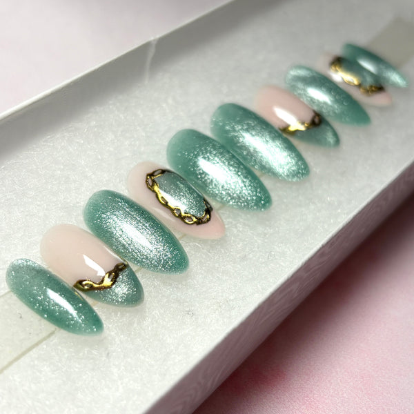 Load image into Gallery viewer, Short almond press-on nails in green cat eye with delicate gold chrome accents, in a white presentation box.