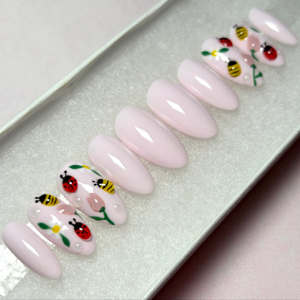 Load image into Gallery viewer, Spring press-on nails in pastel pink with 3D ladybirds, bees and flowers artwork, in a short almond shape, displayed in a white presentation box.