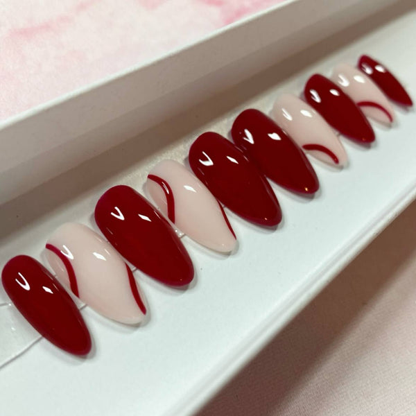Load image into Gallery viewer, Short almond press-on nails painted in a deep burgundy red color with natural tips and burgundy lines, in a white presentation box.