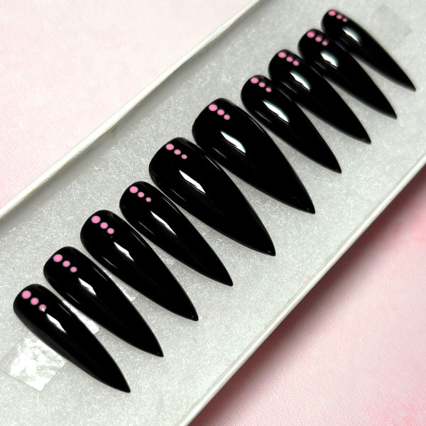 Load image into Gallery viewer, Black stiletto press-on nails with pink dots on a white tray against a pink background