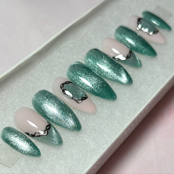 Load image into Gallery viewer, Fake nails in a long almond shape, with shimmery sage-green cat eye and soft pink, accented by two green cat-eye French tips and a delicate silver chrome 3D chain design, in a white presentation box.