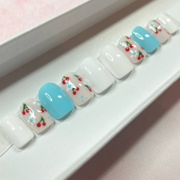 Load image into Gallery viewer, Short square summer press-on nails featuring delicate cherries and floral designs on a white and blue background, displayed in a white presentation box.