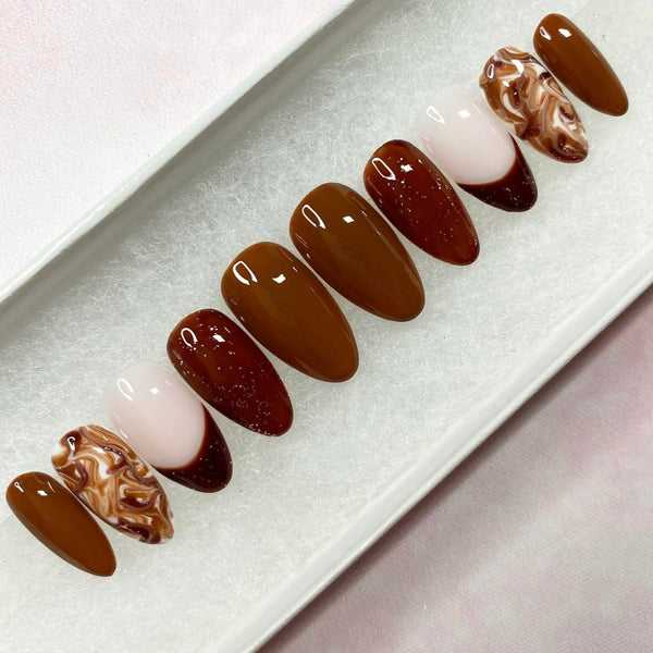 Load image into Gallery viewer, French tip handmade press-on nails in various tones of brown with subtle glitter and a marble effect pattern, in a white presentation box.