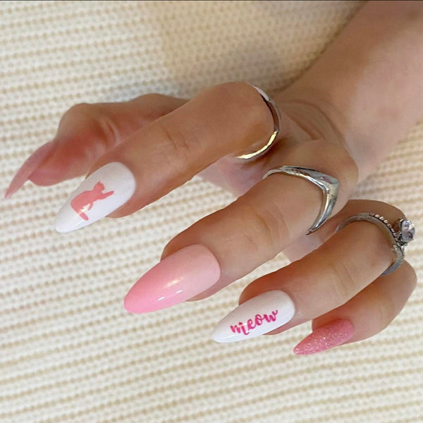 Load image into Gallery viewer, A hand wearing almond-shaped false nails featuring various designs including solid pink glitter, pink ombre gradients, solid pink ombre, white with pink cat silhouettes, and white with pink script text reading 'meow'.