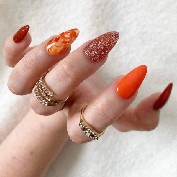 Load image into Gallery viewer, Hand wearing long almond press-on nails in tones of orange and brown, as well as multiple rings.