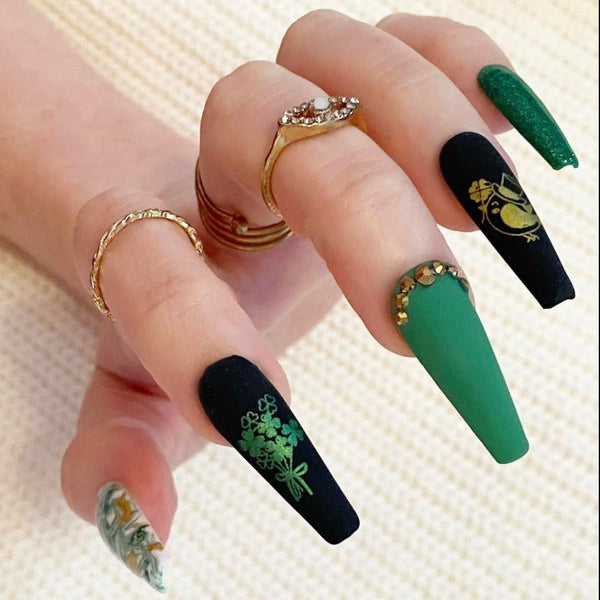 Load image into Gallery viewer, Hand wearing St Patrick's Day handmade press-on nails in green, black and gold with bird and shamrocks designs, rhinestones and glitter