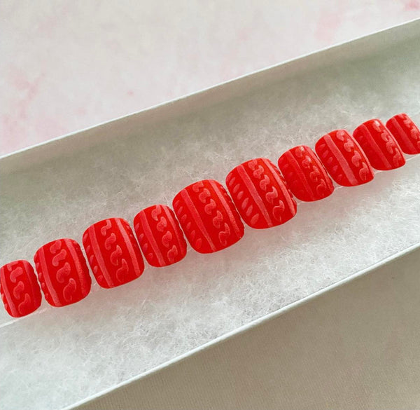 Load image into Gallery viewer, Christmas false nails in red with a 3D shimmery sweater pattern design that resembles frost, in a short square shape and displayed in a white presentation box.