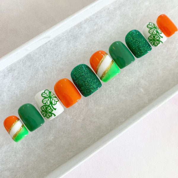 Load image into Gallery viewer, St Patrick's Day handmade press-on nails in green, orange, white and gold with a lucky clover design and glitter, from Illuminate by Liana