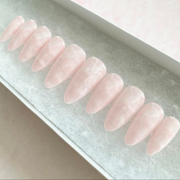 Load image into Gallery viewer, Almond shaped fake nails that resemble rose-quartz gemstone crystals, in a soft pink with a white marbling pattern throughout, displayed in a white presentation box.