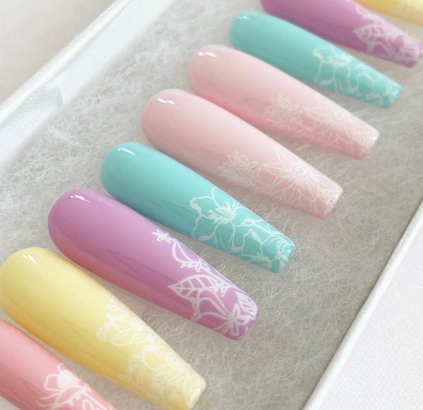 Load image into Gallery viewer, Floral press-on nails in pastel colours with a white floral design on each nail, in a long coffin shape.