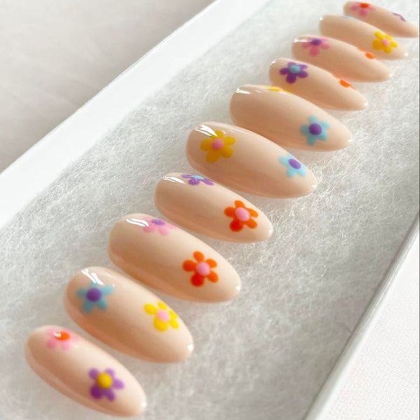 Load image into Gallery viewer, Set of floral press-on nails in a short almond shape, featuring flowers in various colours on a pastel cream beige base.