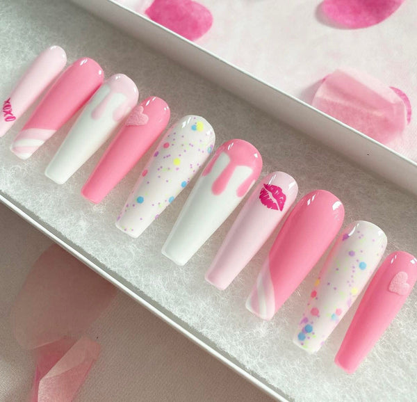 Load image into Gallery viewer, Pink and white false in various shades of pink, featuring a lips and xoxo design, drip artwork, and 3D hearts all in pink, and confetti style glitter, in a white presentation box with pink petals in the background.