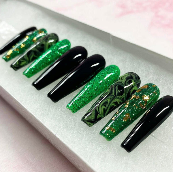 Load image into Gallery viewer, A set of handmade press-on nails in a long coffin shape, in green, black and gold, featuring a green and black marble design, gold-leaf/foil accents, and subtle glitter, displayed in a white presentation box.