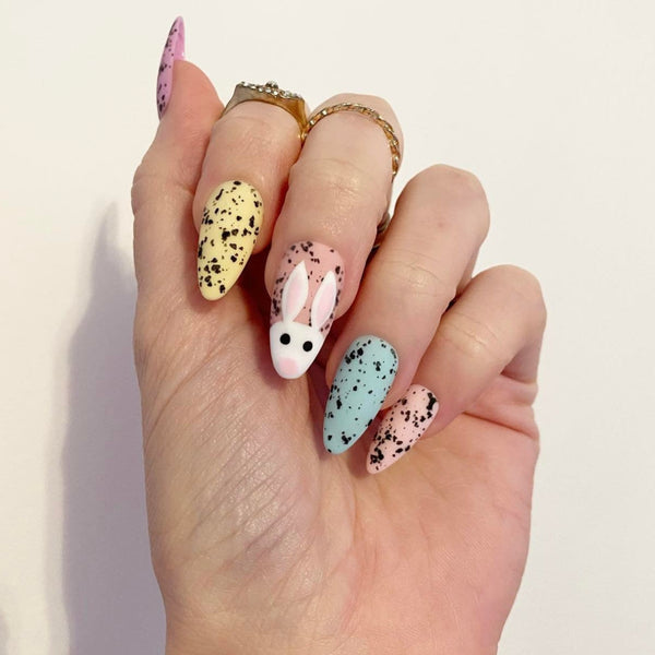Load image into Gallery viewer, Handmade Easter press-on nails in pastel colors with speckled eggshell pattern and cute rabbit design in pale yellow, blue, orange, and pink, from Illuminate by Liana