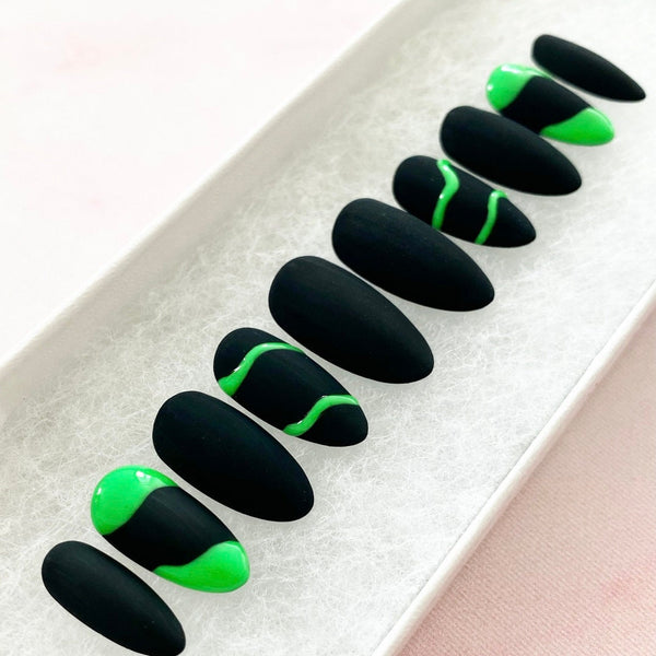 Load image into Gallery viewer, Short press-on nails in matte black with a neon green wavy line and abstract design on four of the nails, in a white presentation box.