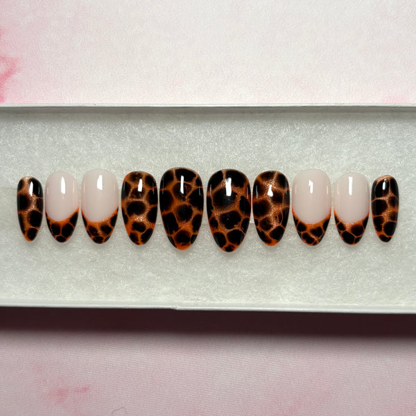 Load image into Gallery viewer, Stick-on nails featuring an animal print design that resembles leopard print or tortoiseshell in copper and deep brown-black, as well as four French tip nails tipped with the same animal print pattern, displayed in a white presentation box.

